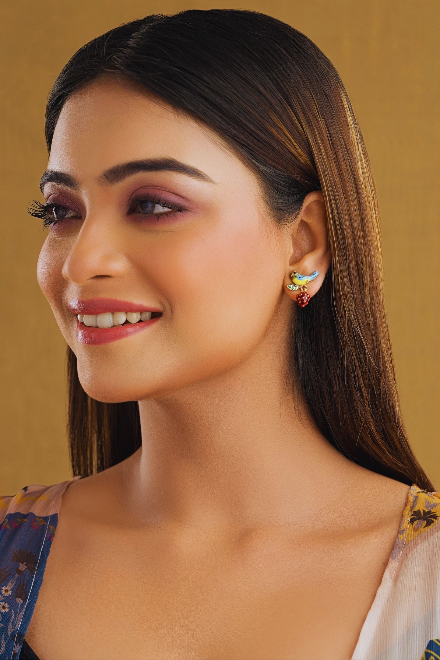 Woman wearing earrings with a gold background