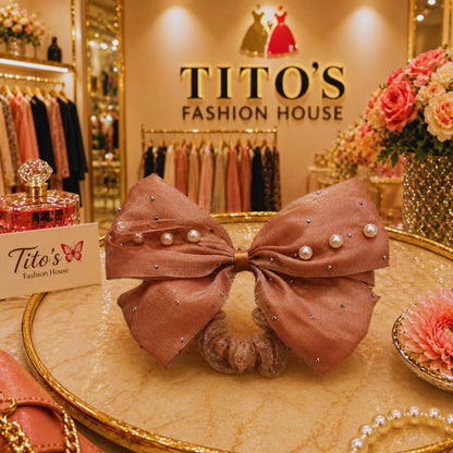 Decorative bow with pearls on a table in front of Tito's Fashion House sign.