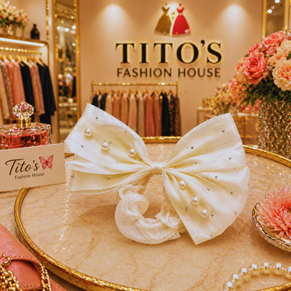 White bow with pearls on a table in a fashion store with 'Tito's Fashion House' branding.