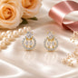 Gold and diamond earrings on a soft surface with roses and a ribbon.