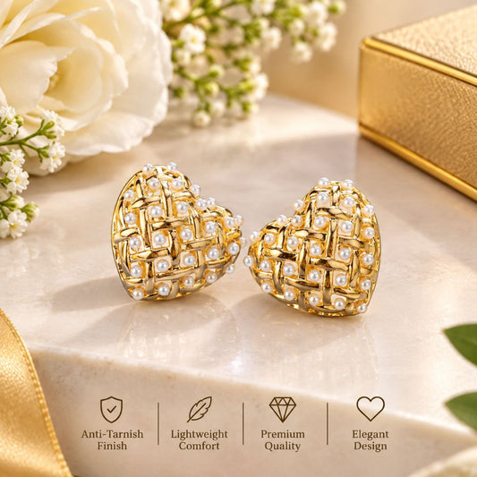 A pair of gold heart-shaped stud earrings decorated with woven mesh and small white pearls, displayed on a marble surface with white flowers, a gold box, and feature icons at the bottom.