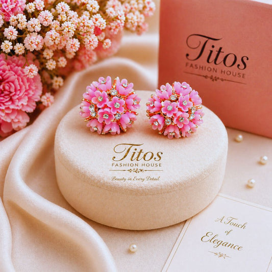 Pink floral earrings on a 'Titos Fashion House' branded box with pink flowers in the background.