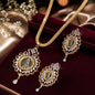 Gold-toned jewelry set with a necklace and matching earrings, featuring ornate filigree details and central coin-like medallions, displayed on a dark burgundy velvet surface with soft satin fabric and decorative flowers in the background.