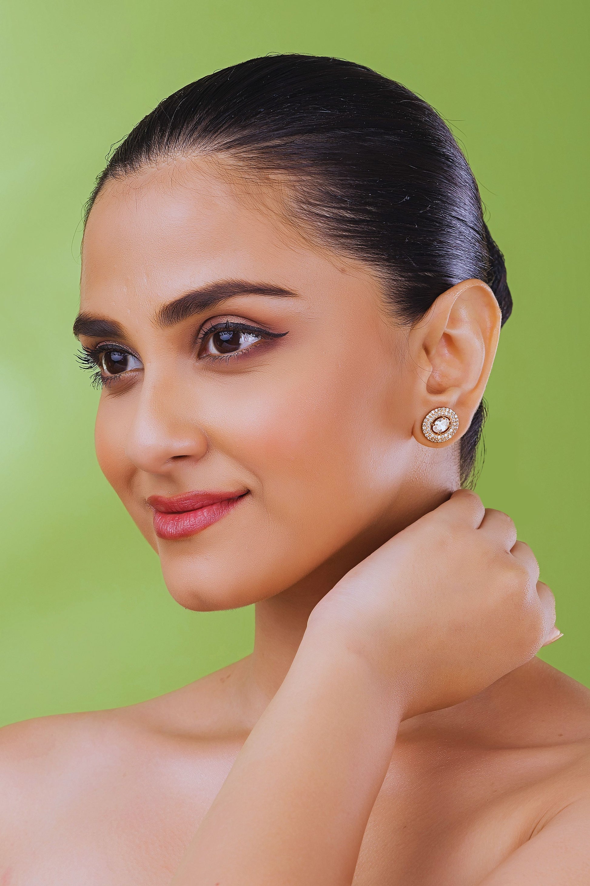 Woman wearing earrings against a green background