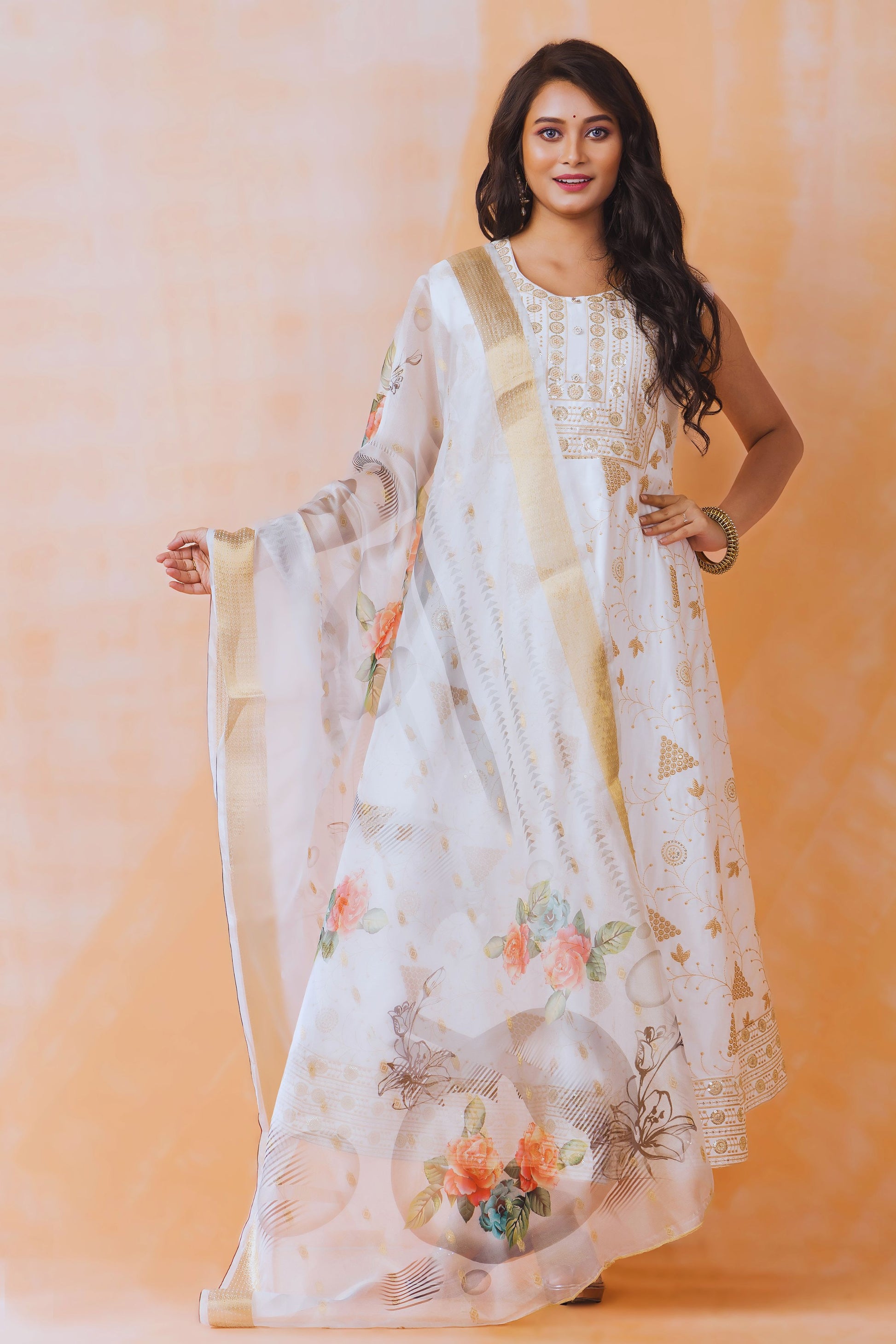 Woman wearing a white floral dress with a beige dupatta against an orange background