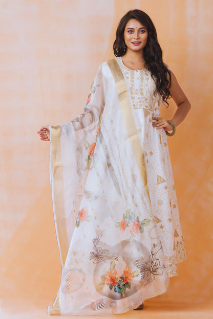 Woman wearing a white floral dress with a beige dupatta against an orange background