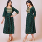 Green dress with gold embroidery worn by a model on a plain background