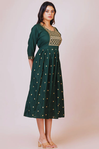 Woman wearing a green dress with gold embroidery on a beige background