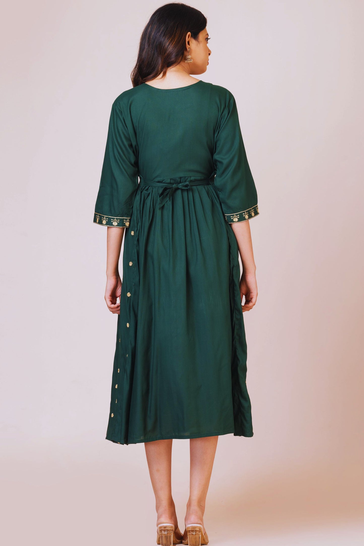 Woman wearing a green dress with a belt against a beige background