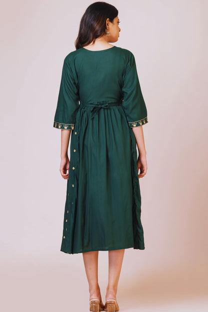 Woman wearing a green dress with a belt against a beige background