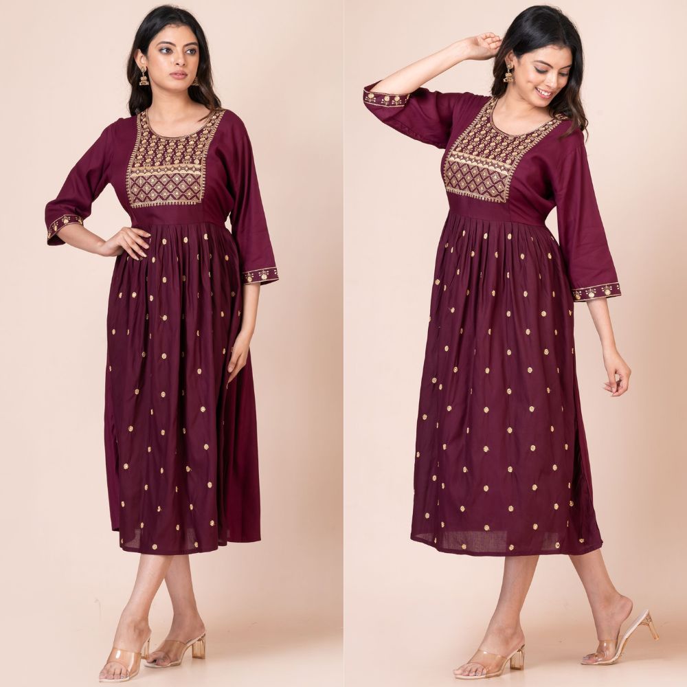 Woman wearing a maroon dress with gold embroidery on a beige background