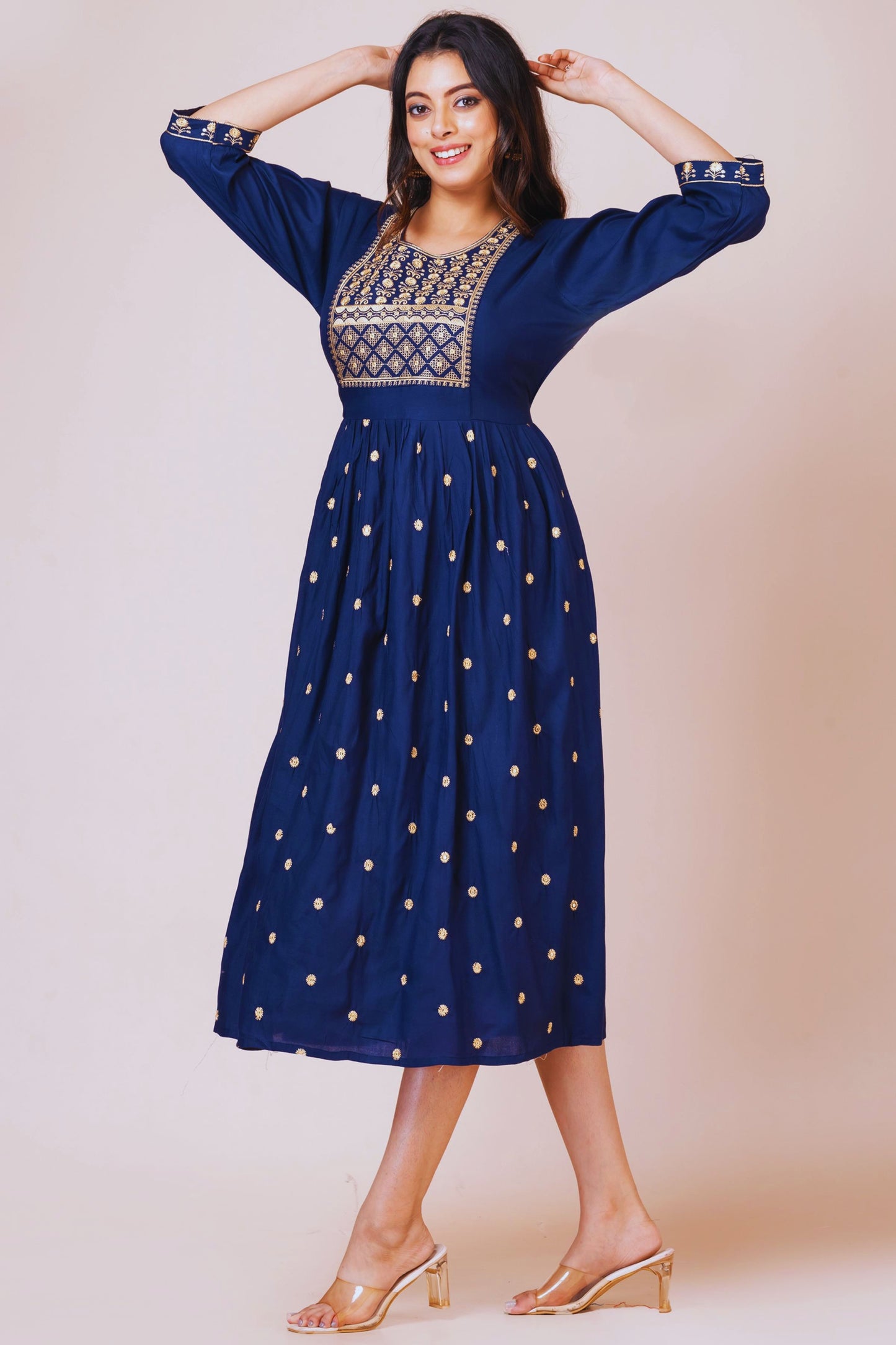 Woman wearing a blue dress with gold patterns on a beige background