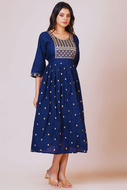 Woman wearing a blue dress with gold embroidery on a beige background