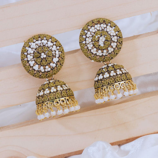 Decorative earrings with gold and green design on a wooden surface