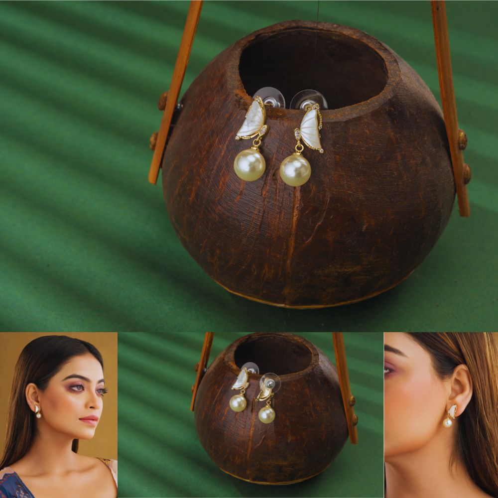 Pearl earrings displayed in a coconut shell with a green background
