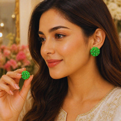 Woman wearing green earrings with a blurred floral background
