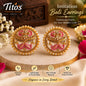 A pair of ornate gold-toned imitation Bali earrings with pink floral inlay and bead borders, displayed on a wooden slice with decorative flowers and text overlays from Tito's Fashion House.