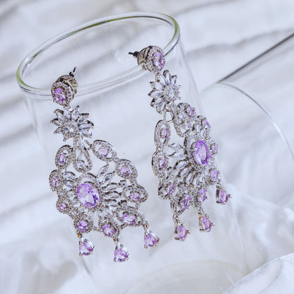 Purple and silver chandelier earrings on a white fabric background