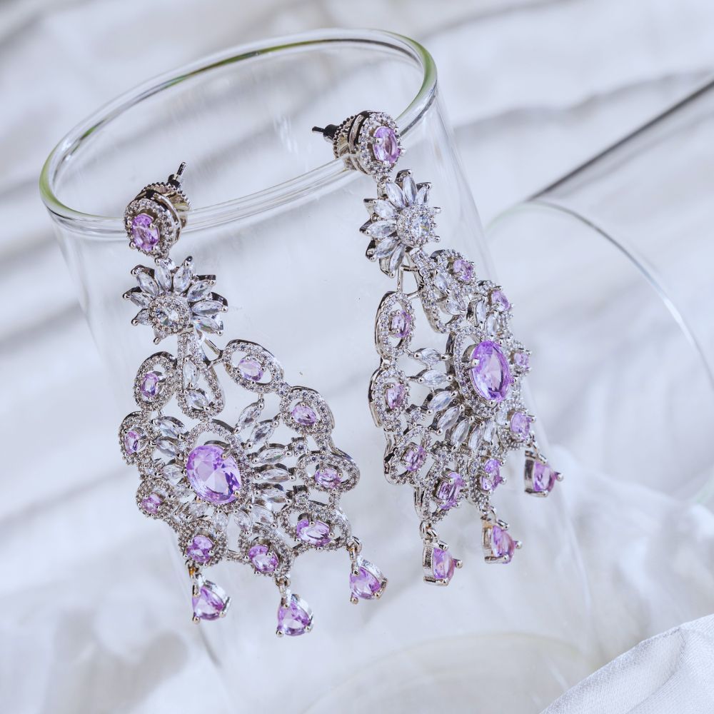 Purple and silver chandelier earrings on a white fabric background