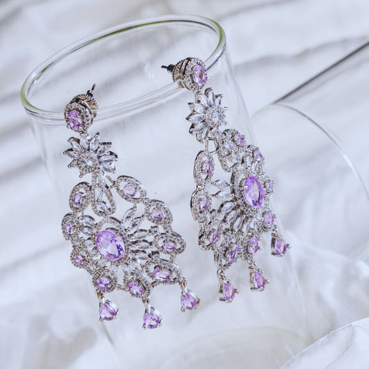 Purple and silver chandelier earrings on a white fabric background