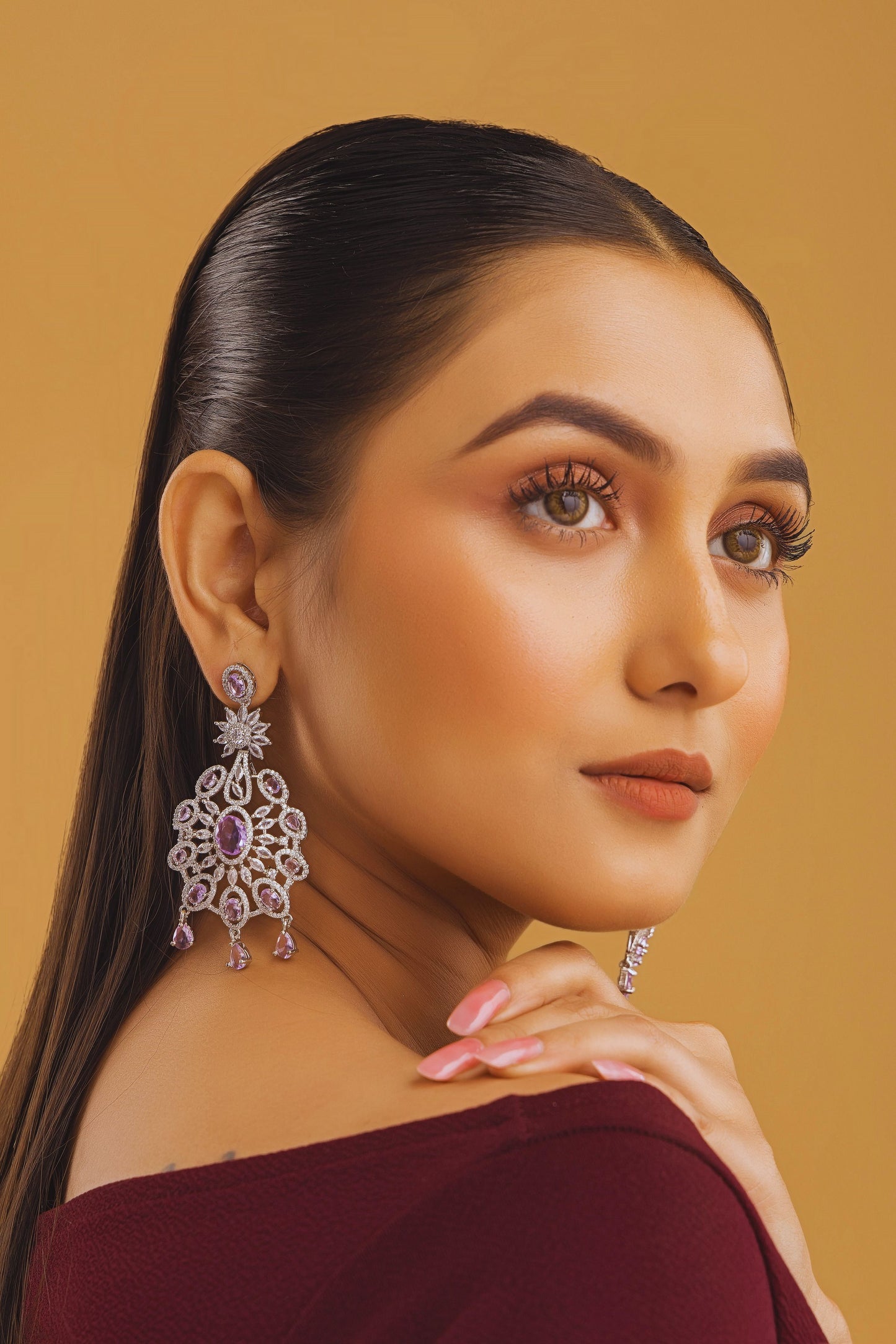 Woman wearing elegant earrings against a warm background