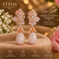A pair of rose gold American diamond drop earrings displayed on a soft brown fabric surface with a warm blurred floral background. The brand name TITOS FASHION HOUSE is visible in the top left, and text on the right reads 'Rose Gold American Diamond Earrings.