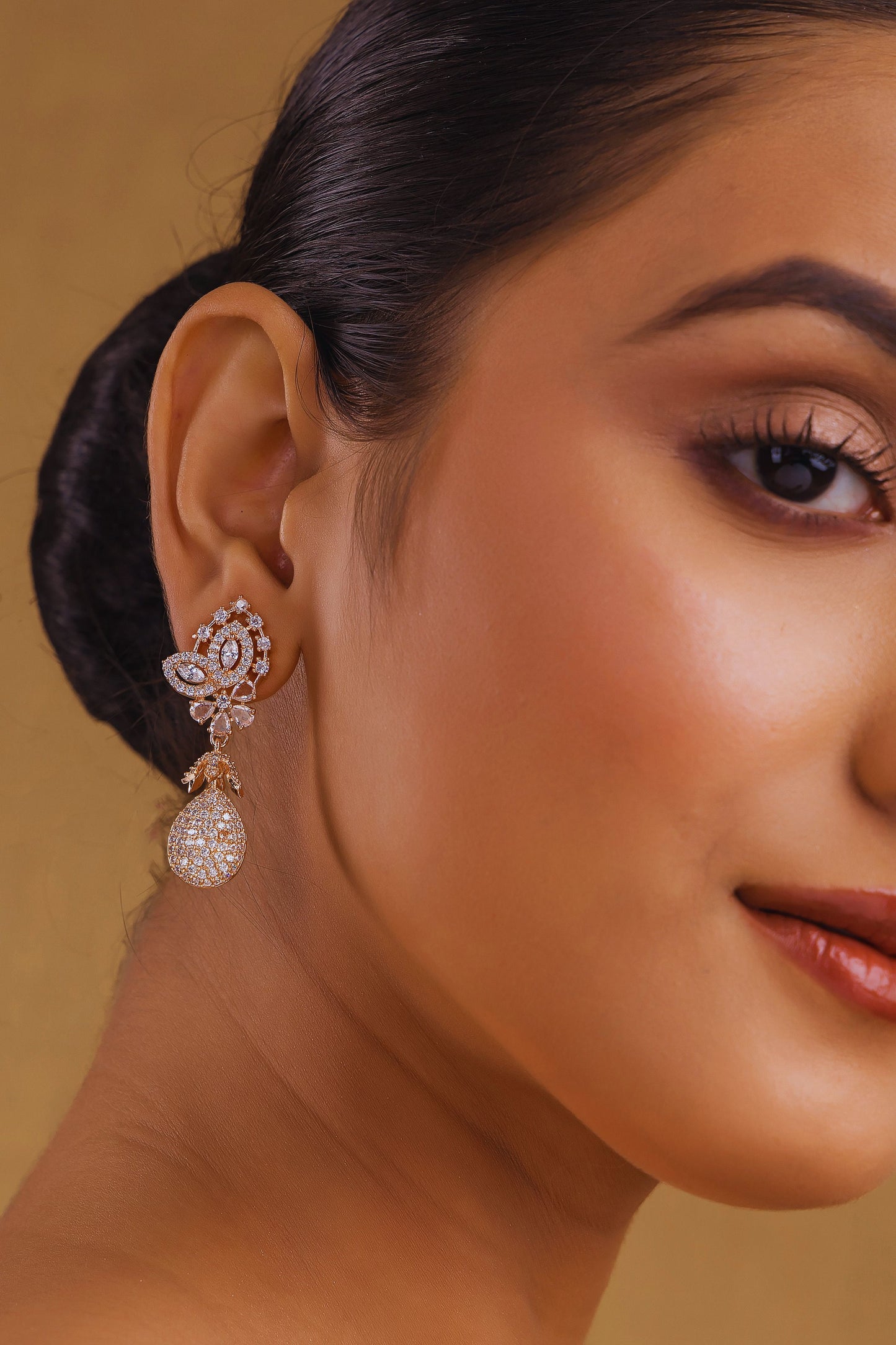 Close-up of a woman wearing a diamond earring with a beige background