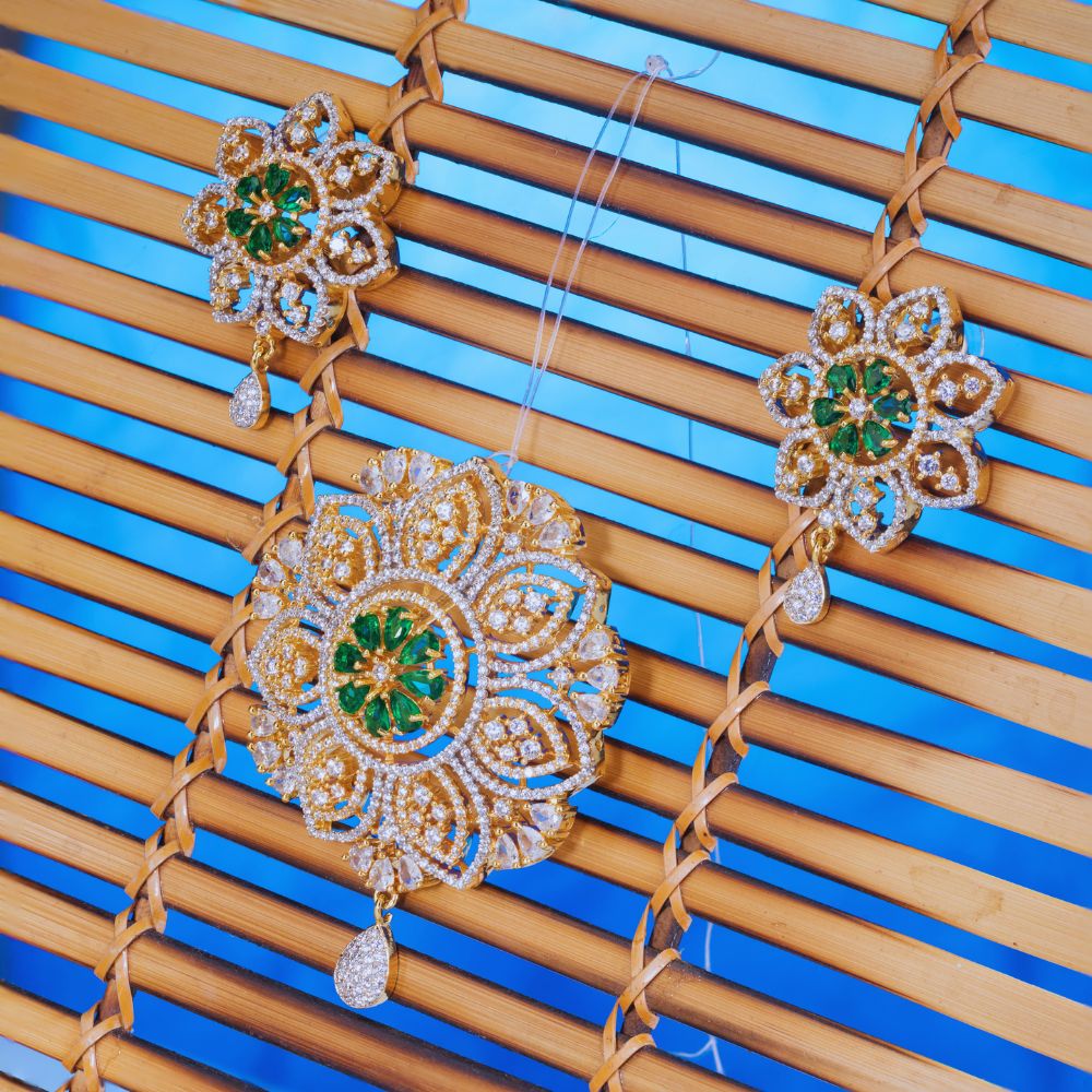 Ornate earrings with green gemstones on a wooden surface with blue background
