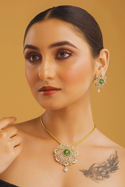 Woman wearing gold jewelry with green gemstones against a beige background