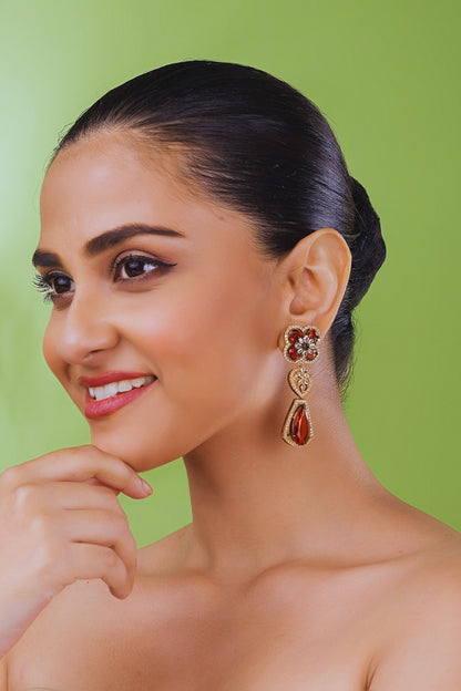 Woman wearing a pair of earrings against a green background