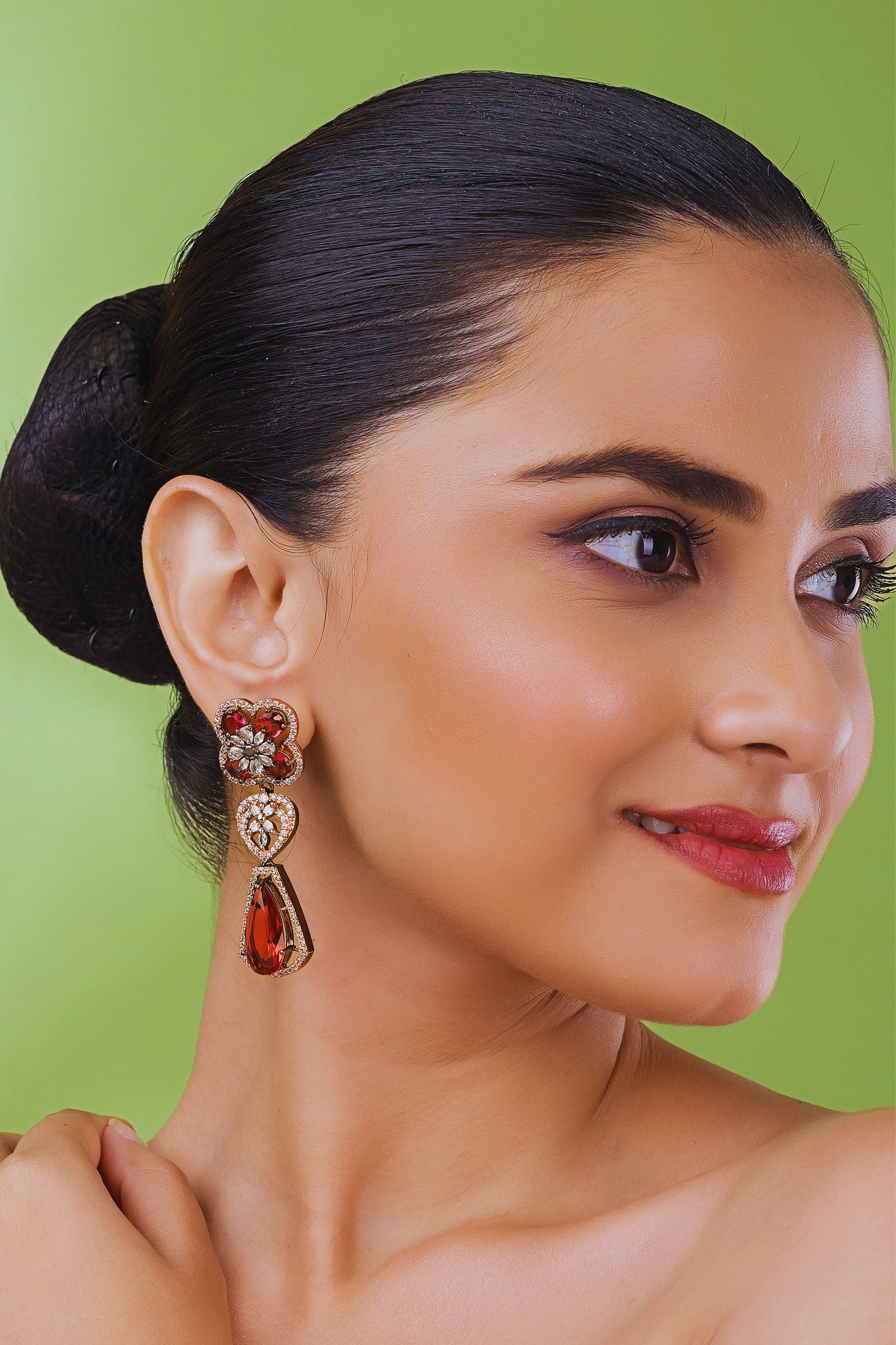 Woman wearing a pair of earrings with a green background