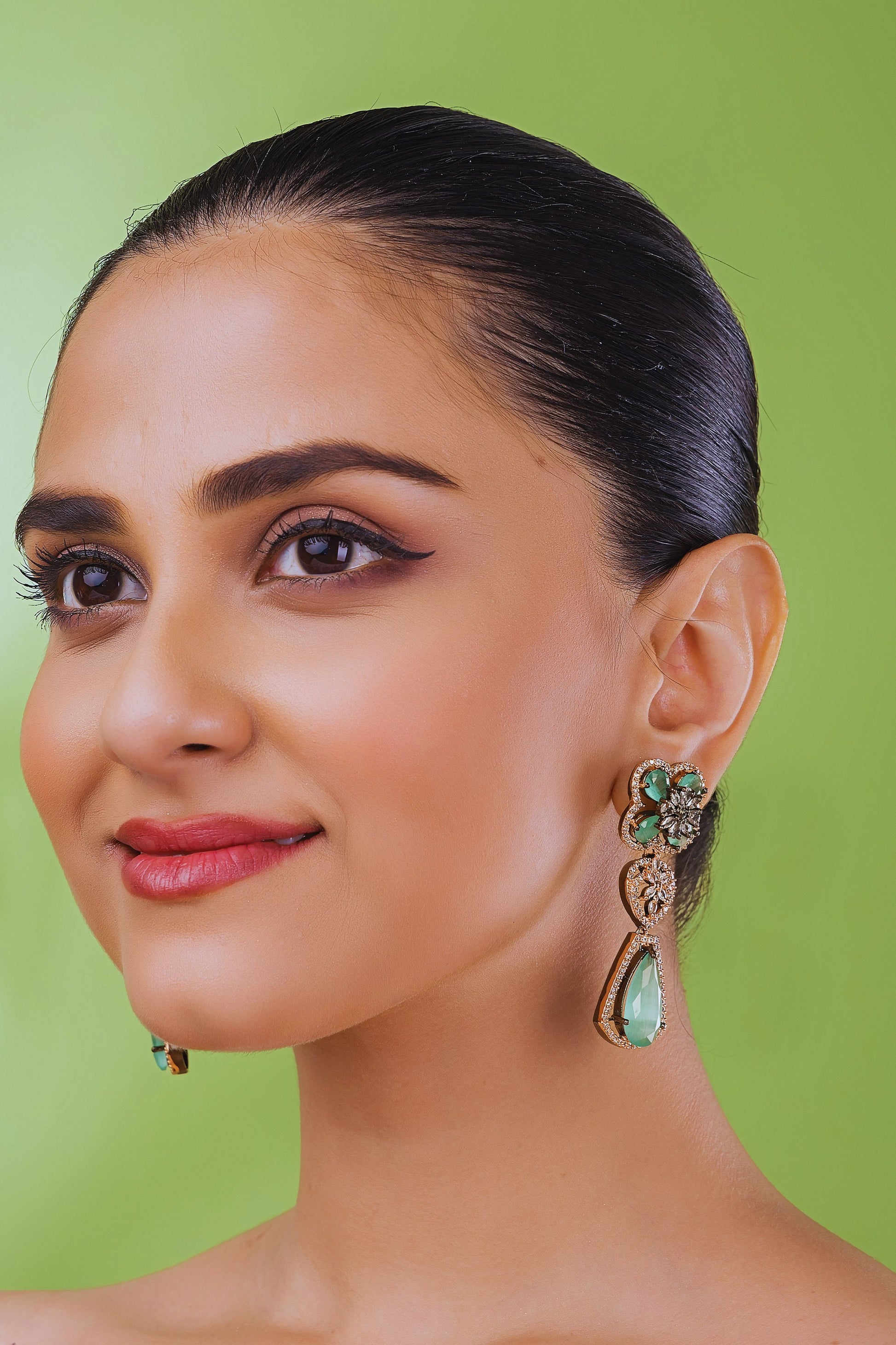 Woman wearing earrings with a green background