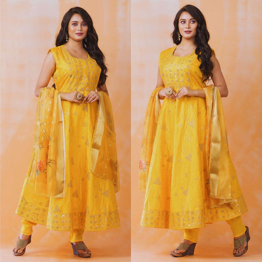 Woman wearing a yellow traditional outfit with a dupatta against an orange background