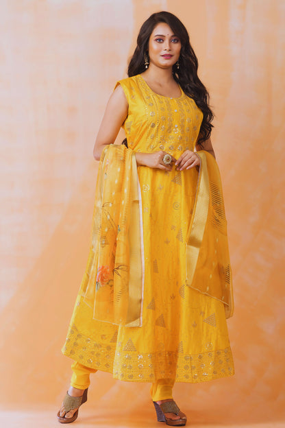 Woman wearing a yellow traditional outfit with a matching dupatta against an orange background