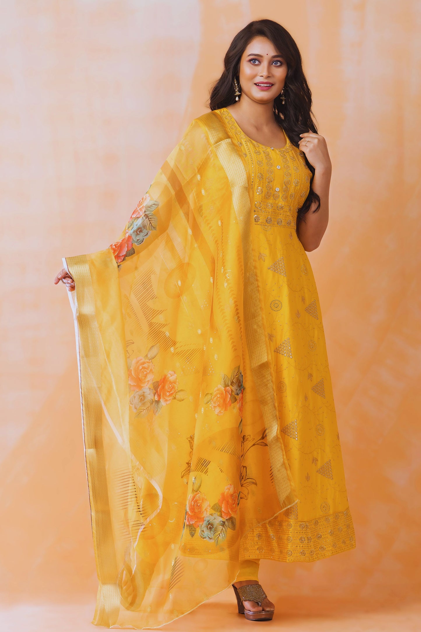 Woman wearing a yellow floral dress against an orange background