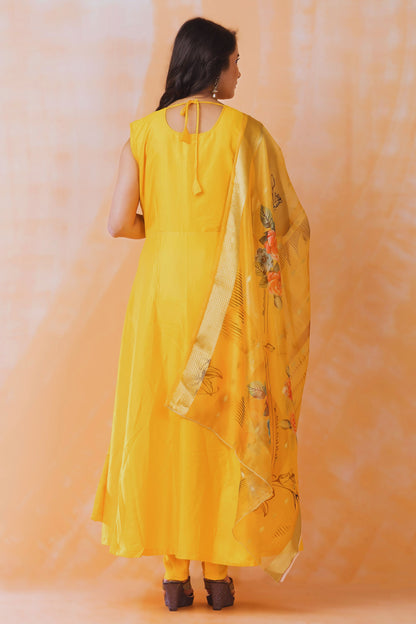 Woman wearing a yellow traditional outfit with a dupatta against an orange background