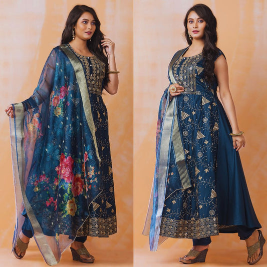 Woman wearing a blue embroidered outfit with a floral dupatta on an orange background
