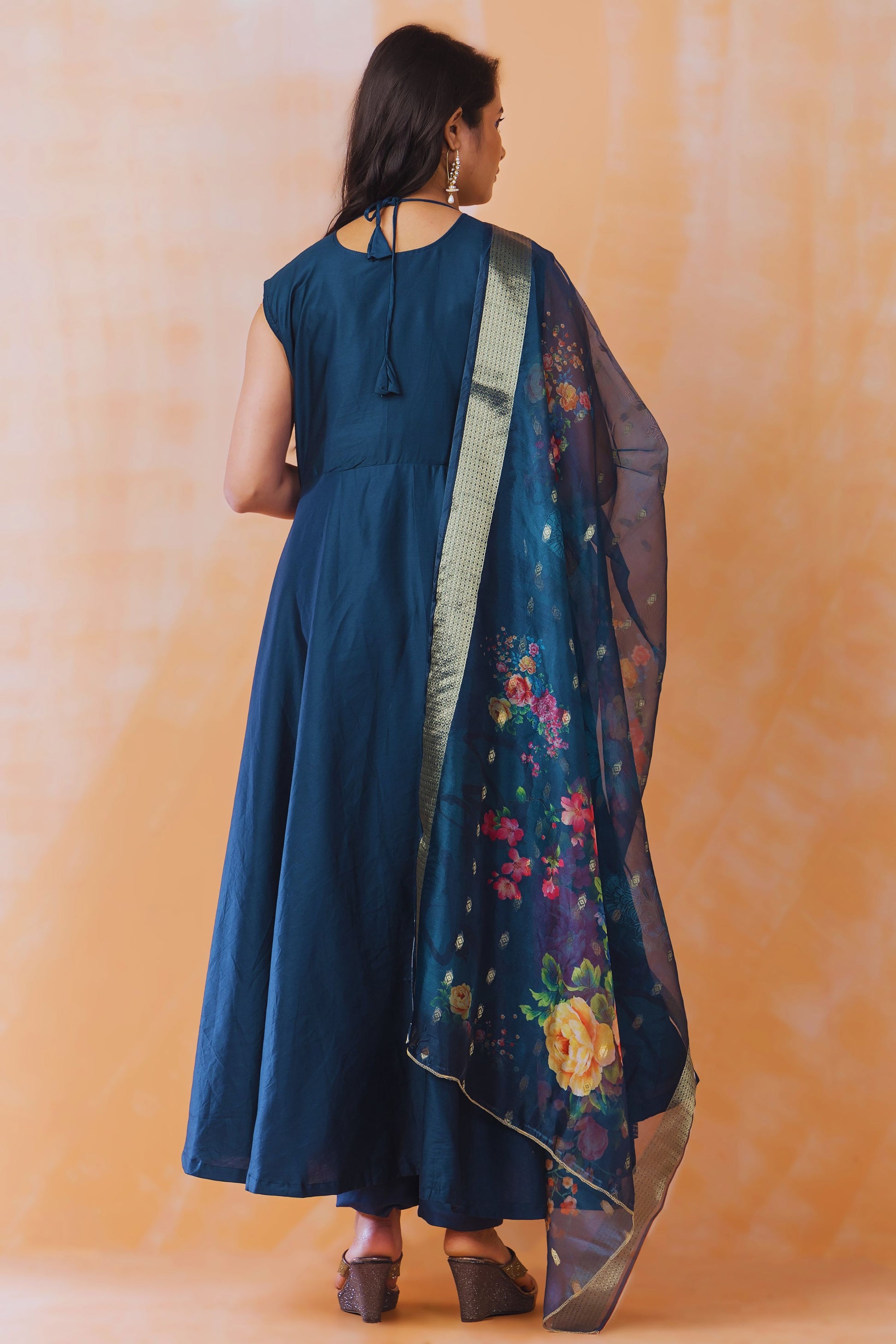 Woman wearing a blue dress with a floral dupatta against an orange background
