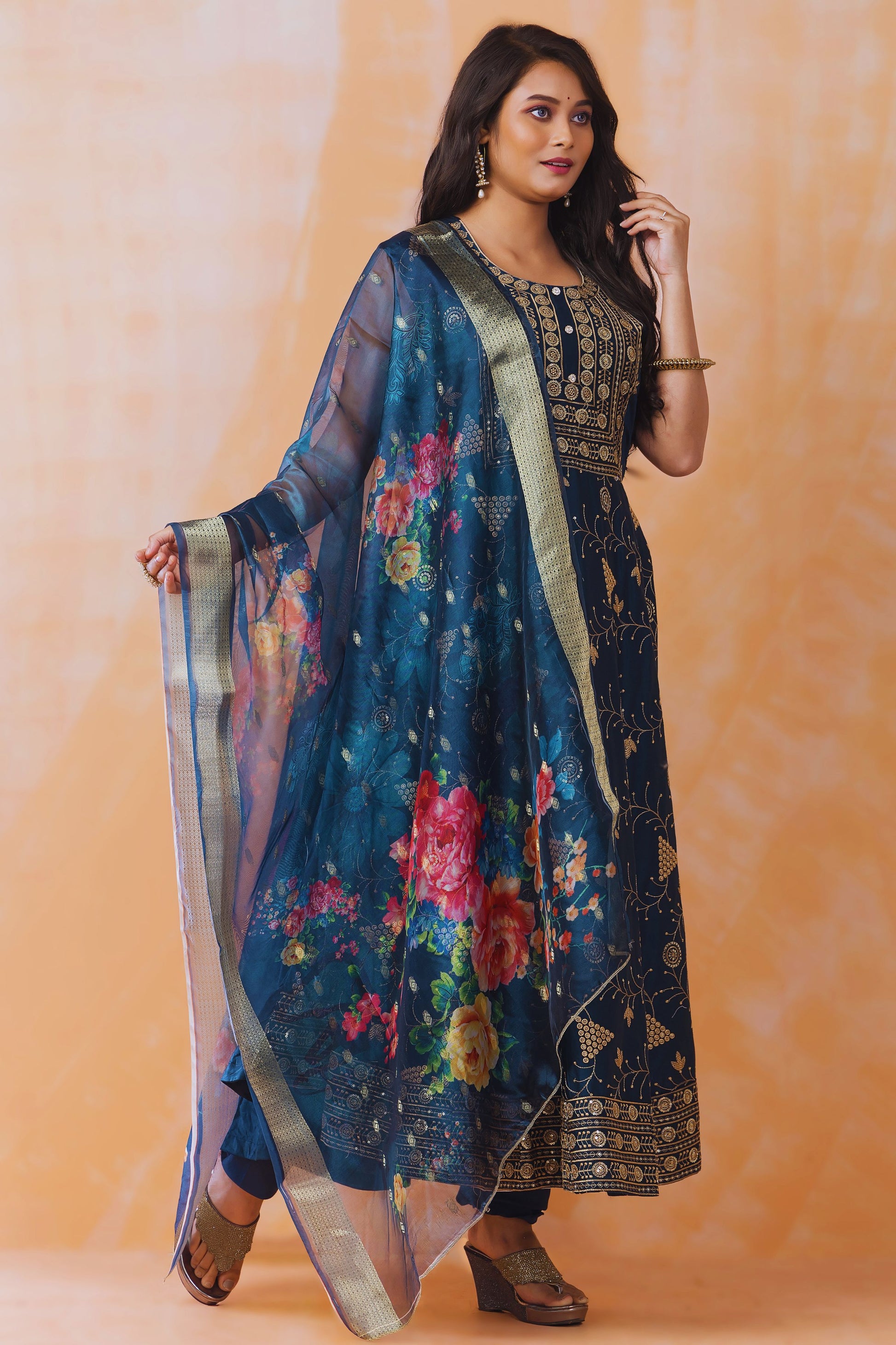 Woman wearing a traditional outfit with a floral design against an orange background