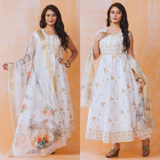 Woman wearing a white embroidered dress with a floral dupatta against an orange background