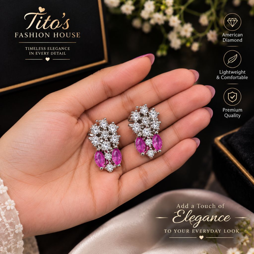 A hand holding a pair of silver-toned dangle earrings with clear stones and pink gemstone drops, set against a dark background with a black gift box and decorative text overlays.