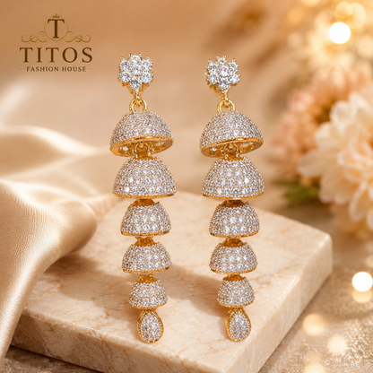 Gold and diamond earrings on a marble surface with 'TITOS Fashion House' branding.