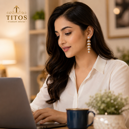 Woman using a laptop with a cup of coffee and a plant in the background, featuring the TITOS Fashion House logo.