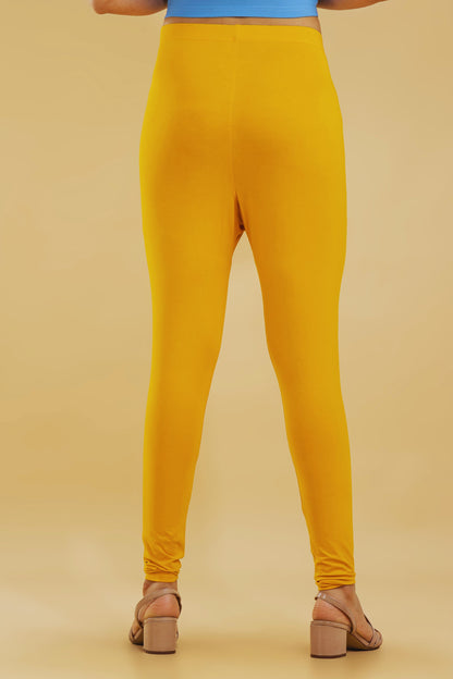 Mustard yellow leggings worn by a person on a beige background