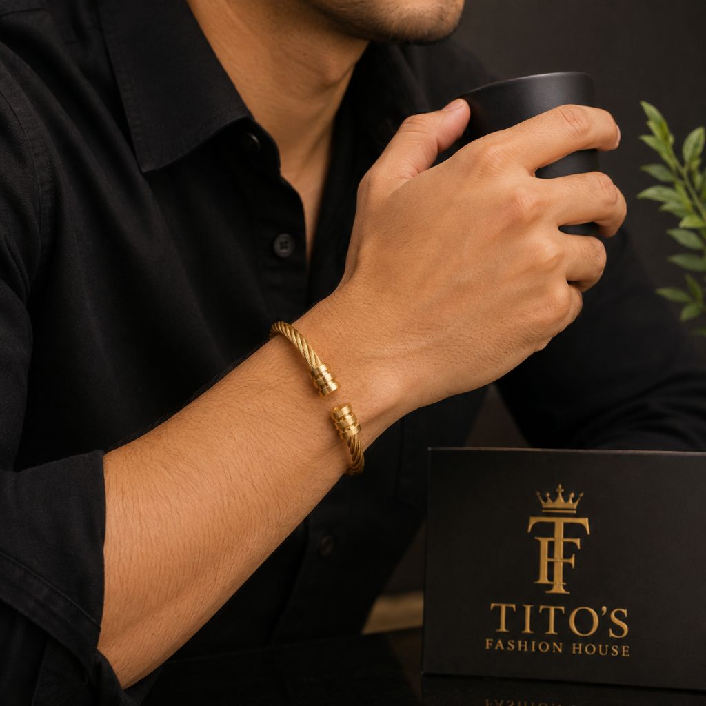 A man wearing a gold twisted rope bracelet with a gold clasp, holding a black mug next to a black gift box branded 'TITO'S FASHION HOUSE'.