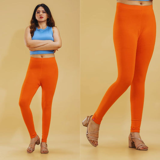 Woman wearing bright orange leggings with a plain background