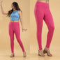 Woman wearing pink leggings and a blue top on a beige background