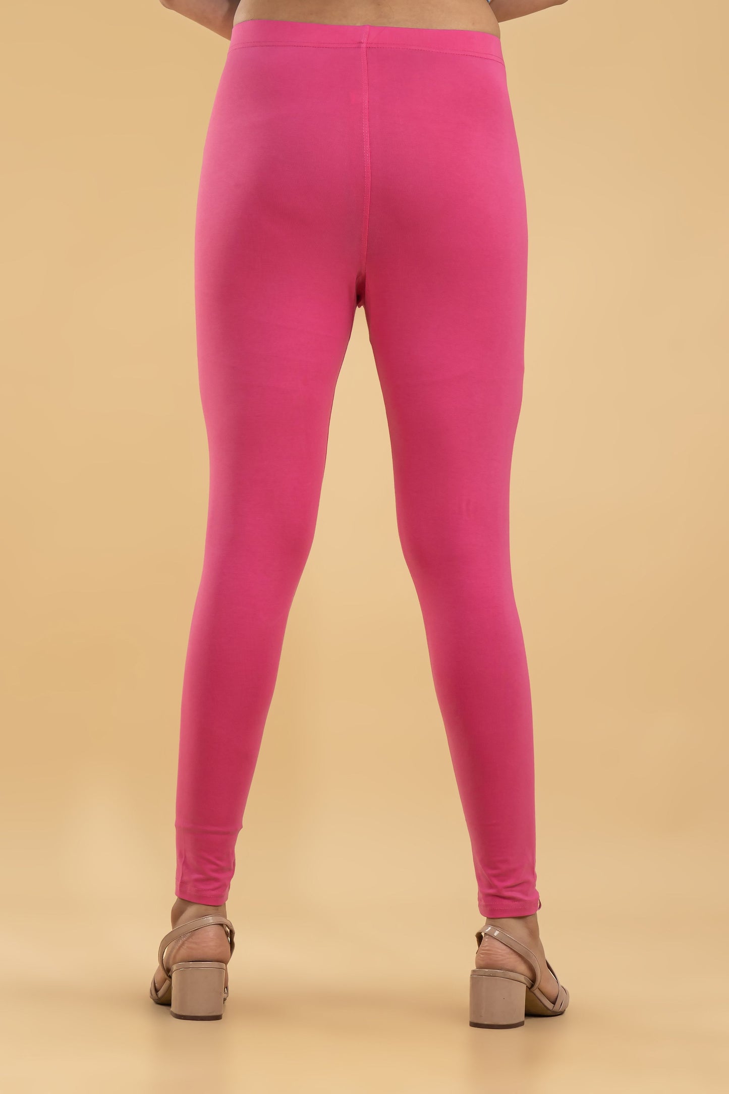 Person wearing bright pink leggings on a beige background