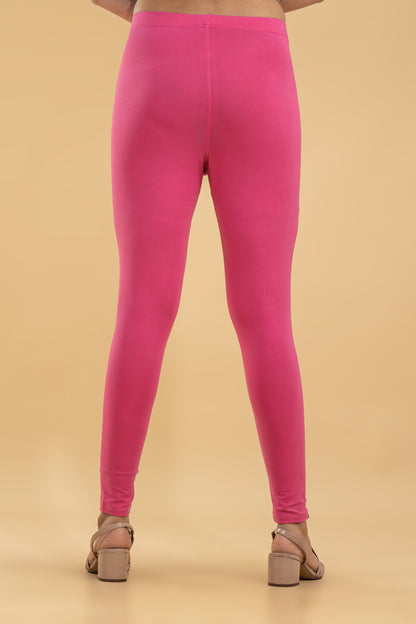 Person wearing bright pink leggings on a beige background