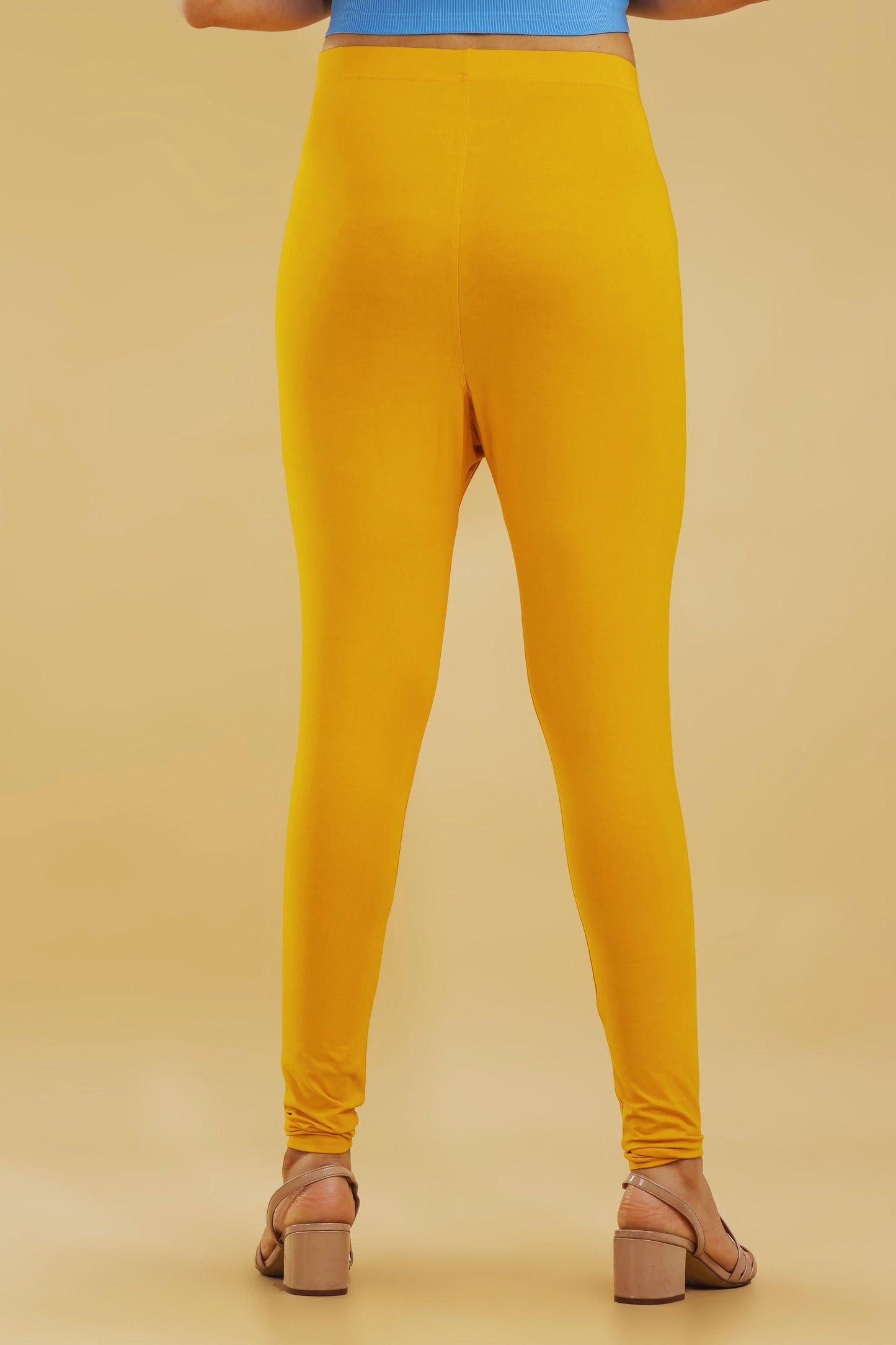 Mustard yellow leggings worn by a person on a beige background